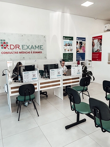 foto da recepção da unidade, com longarina com cadeira e uma estação de atendimento com 2 atendentes